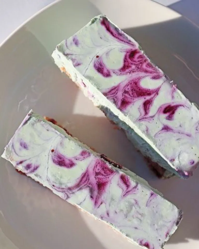 Close-up of purple-and-white marbled cheesecake bars on a light surface.