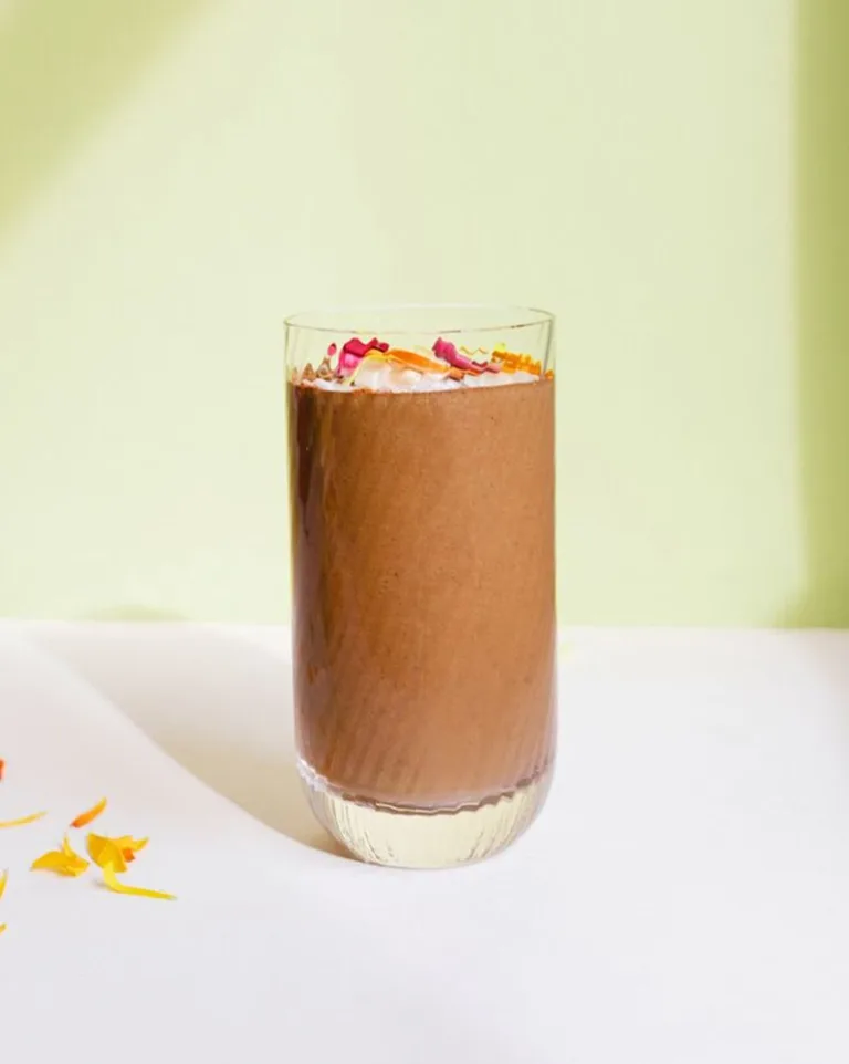 Glass of Metabolism Super Powder chocolate smoothies, topped with coconut flakes.