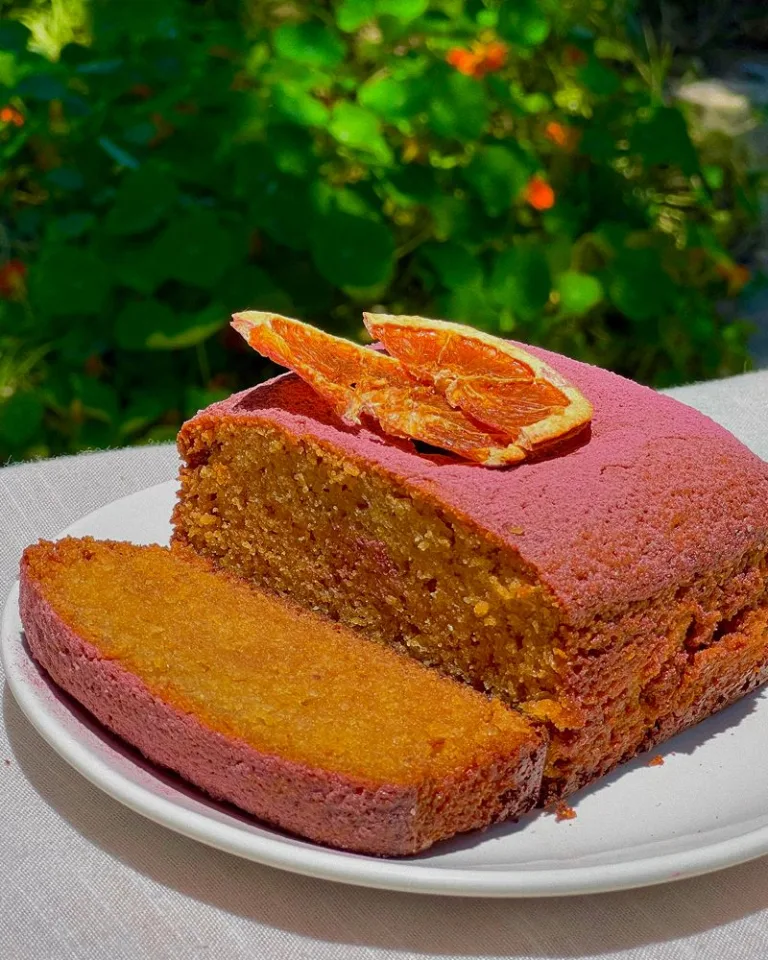 Citrus olive oil cake topped with dried orange slices, with one slice cut and plated.