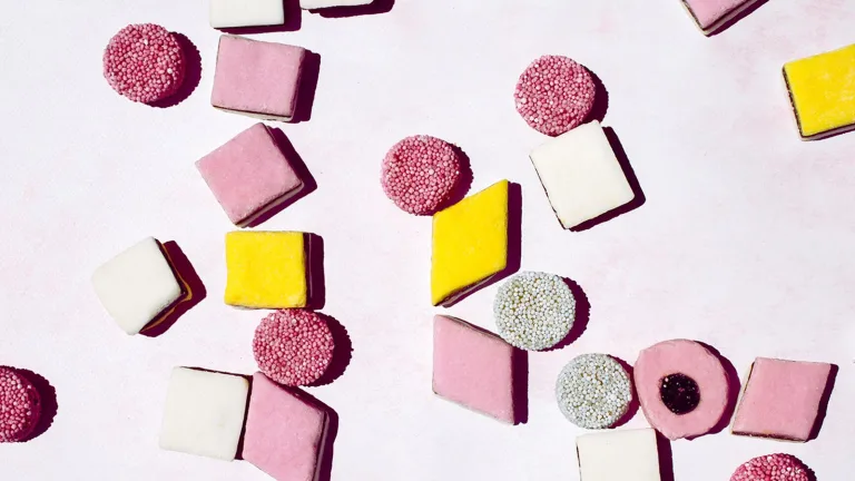 Assorted pastel-colored candies arranged on a light pink background.