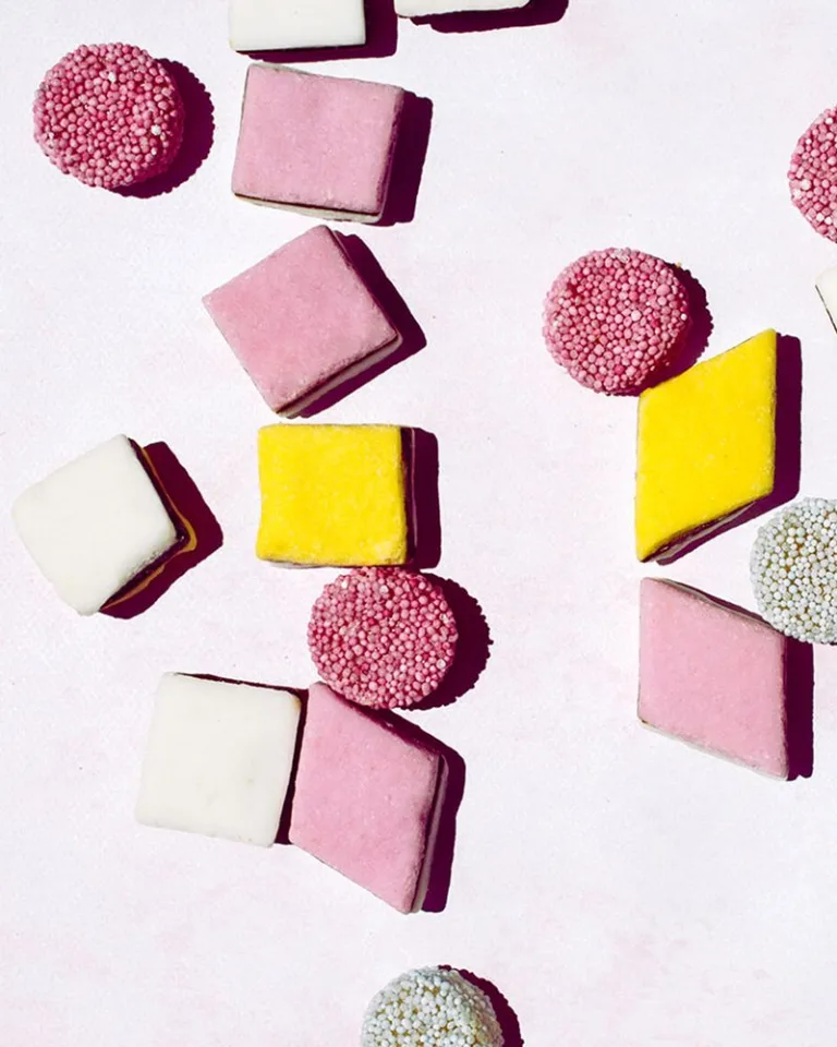 Assorted pastel-colored candies arranged on a light pink background.