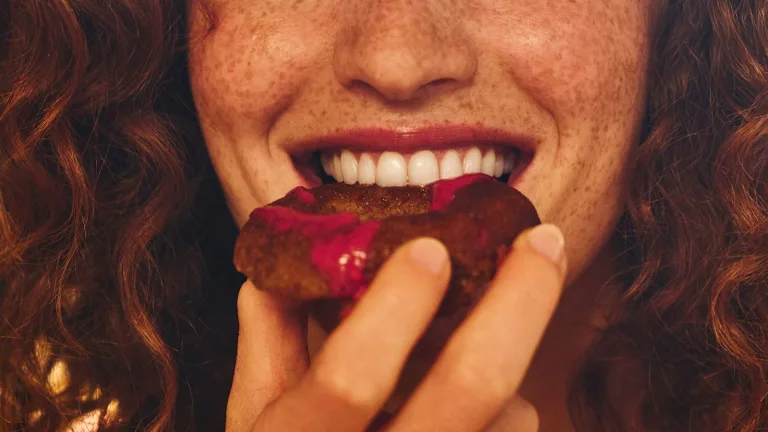 Close-up of a woman biting into a donut.
