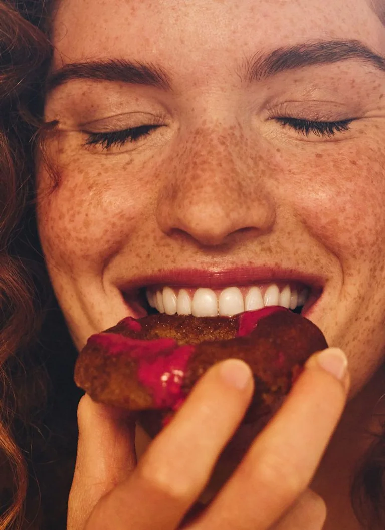 Close-up of a woman biting into a donut.