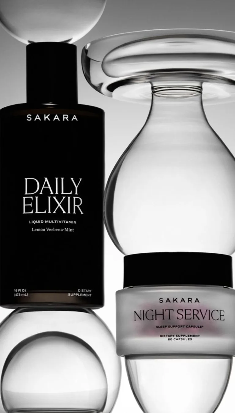 Sakara Life Daily Elixir and Night service packaging in an editorial photoshoot/position, stacked on top and between glass objects